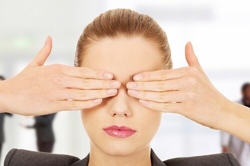 Young businesswoman covering eyes with hands.